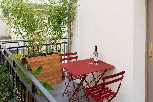 a red table with two wine glasses on a balcony at Joli Duplex Confort T2 Paris Porte De Versailles in Vanves