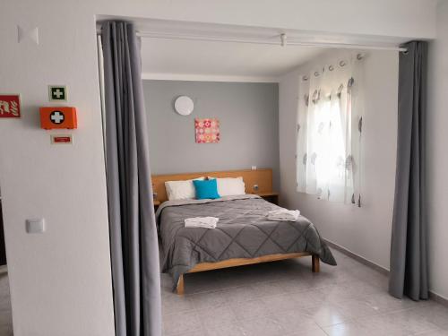 1 dormitorio con 1 cama con almohadas azules en Apartamentos Campos 1, en Porto Covo