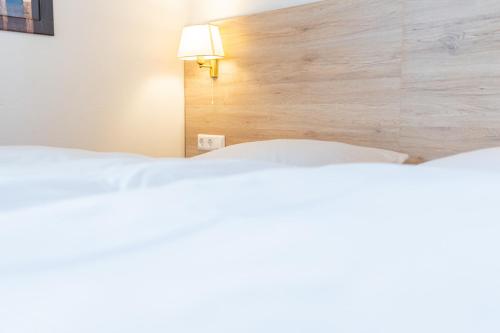 a bedroom with two white beds and a wooden headboard at Hotel am Römerplatz in Ulm