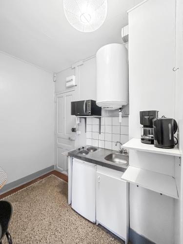 une cuisine blanche avec un évier et un comptoir dans l'établissement Vue Sur la Ville - Studio Angers - proche gare, à Angers