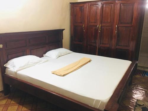 a bed with a wooden headboard and white sheets at NICE APARTMENT in Kituoni