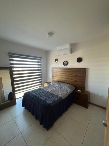 Wayckhome في غواذالاخارا: غرفة نوم مع سرير مع اللوح الأمامي الخشبي ونافذة