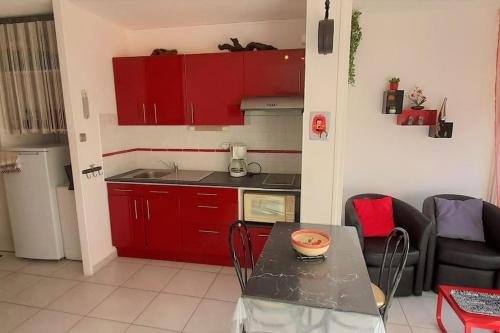 - une cuisine avec des placards rouges et une table dans une pièce dans l'établissement Studio 26, Héliopolis E au village naturiste, au Cap d'Agde