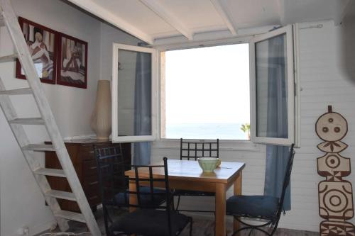 une salle à manger avec une table et des chaises et une fenêtre dans l'établissement Face à la plage, climatisation, WiFi, parking, tout à pied, idéal vacances, à Six-Fours-les-Plages