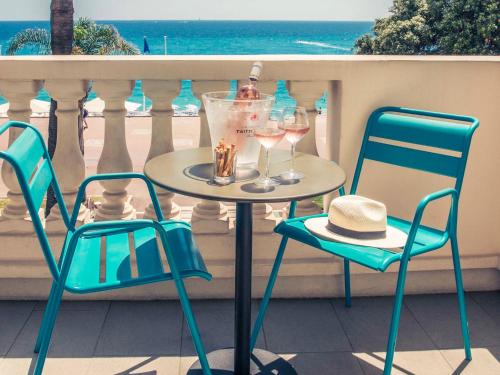 une table avec deux chaises et des verres à vin sur un balcon dans l'établissement Mercure Nice Marché Aux Fleurs, à Nice
