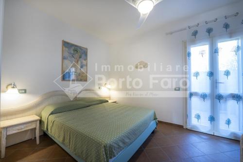 a bedroom with a bed and a table and windows at L301 - Bilocale caposchiera con giardino e vista sulla spiaggia di Porto Mannu in Palau