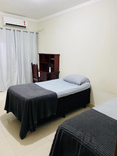a bedroom with two beds and a desk in it at Aluga-se Apartamento todo no Parque Caravelas in Ipatinga