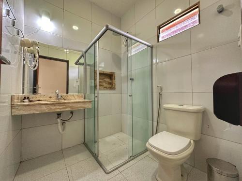 a bathroom with a toilet and a glass shower at Hotel Aconchego do Velho Chico in Piranhas