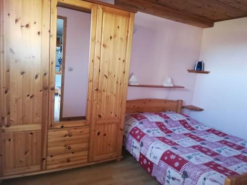 1 dormitorio con 1 cama y armario de madera en Appartement les Crocus rez de jardin maison, en Prémanon