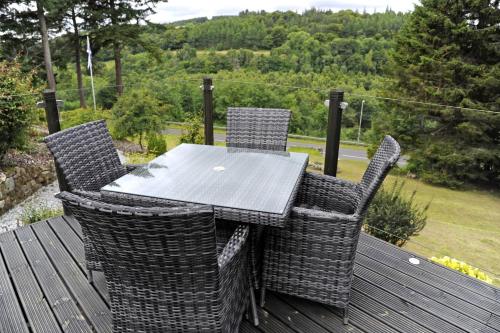 a table and chairs on a deck with a view of a field at The Dowans Hotel of Speyside in Aberlour