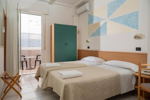 2 Betten in einem Zimmer mit einem Tisch und einem Fenster in der Unterkunft Hotel Leon D'oro in Cattolica