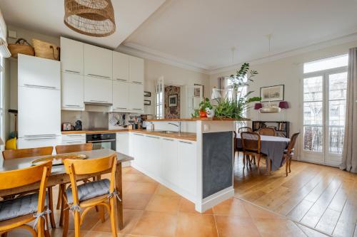 une cuisine avec des armoires blanches et une table et des chaises dans l'établissement Veeve - Flowers in Saint-Martin, à Paris