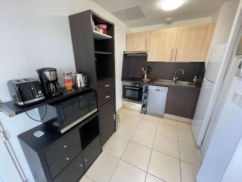 Elle comprend une petite cuisine avec des placards bruns et un évier. dans l'établissement Locations de vacances à Six-fours avec piscine et parking privé et à 800m de la plage, à Six-Fours-les-Plages