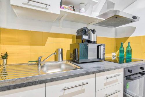 une cuisine avec un évier et un micro-ondes dans l'établissement Appartement Familial proche Saint-Lazarre - 6P, à Paris