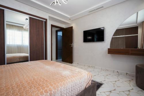 1 dormitorio con 1 cama y TV en la pared en Apart Hotel IMMOKA, en Tánger