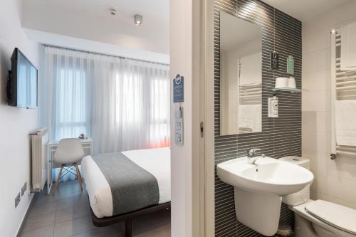 a bathroom with a bed and a sink and a mirror at Alda Soria Rooms in Soria