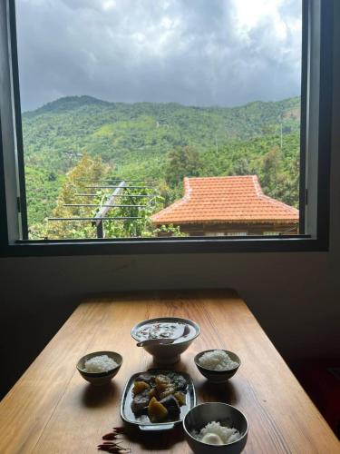 a table with bowls of food and a large window at Lam Nguyên Charming House in Bao Loc