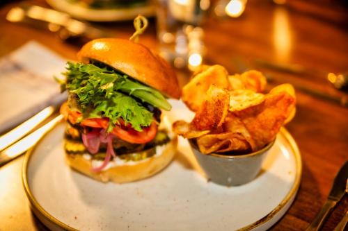 a plate with a hamburger and french fries on a table at Old Orchard Inn in Wolfville