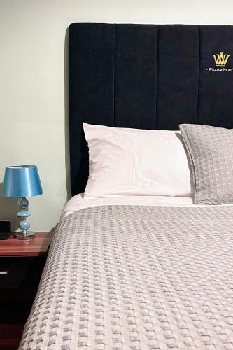 a large bed with a black headboard and a table with a lamp at Penybont Restaurant + Inn in Carmarthen