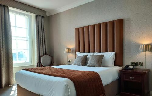 um quarto de hotel com uma cama grande e uma janela em The Western Hotel em Galway