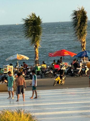 un gruppo di persone in piedi su una spiaggia con ombrelloni di Sun Moon Home 3 a Phan Thiet