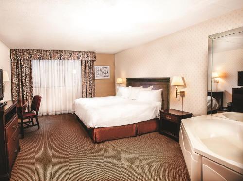 a hotel room with a bed and a tub and a sink at Clifton Victoria Inn at the Falls in Niagara Falls