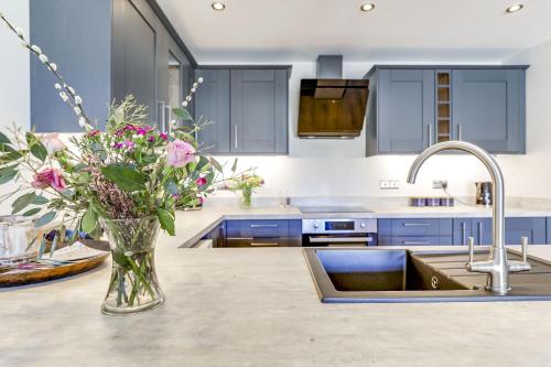 a kitchen with blue cabinets and a vase of flowers at The Old Warehouse Ely "Apartments" in Ely