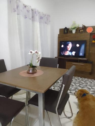 a dog sitting in front of a dining room table at Praia in Praia Grande