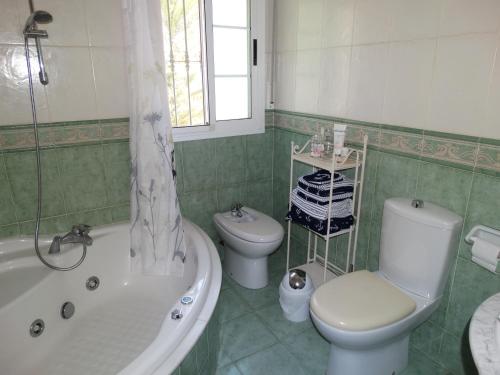uma casa de banho com um WC, uma banheira e um lavatório. em Villa Las Campanas em Periana