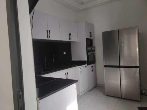 a kitchen with white cabinets and a stainless steel refrigerator at Dapi Home Residence in Lomé