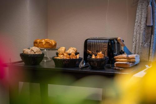 a table with baskets of pastries and a toaster at Hôtel Restaurant Le Madame in La Ferrière