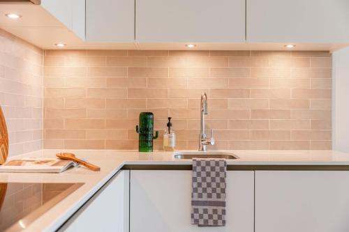 a kitchen with white cabinets and a sink at Huswell - Brand new apartment with terrace - pets welcome! in Ostend
