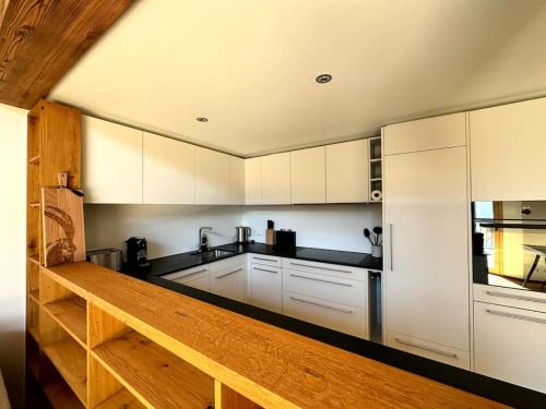 a kitchen with white cabinets and a wooden counter top at Stylish chalet w/Sauna: Alpine escape in Tinzen