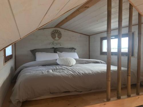 ein Schlafzimmer mit einem großen Bett im Dachgeschoss in der Unterkunft Tiny house à la ferme près Paris et center parcs. in Boissy-sur-Damville