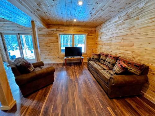 a living room with two couches and a flat screen tv at 65PT New Log Cabin in Private Setting. Hot tub. Gym/Pool Access! in Twin Mountain