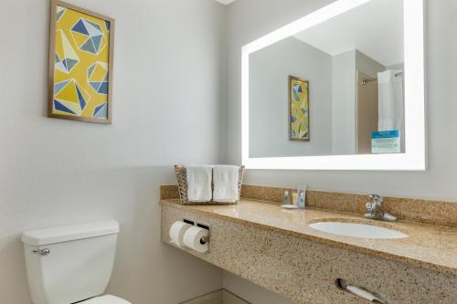 a bathroom with a toilet and a sink and a mirror at Comfort Suites Nacogdoches in Nacogdoches