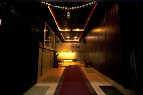 um corredor escuro com um tapete vermelho num edifício em Hotel Sion TriTon - Sion Mumbai Hotels em Mumbai