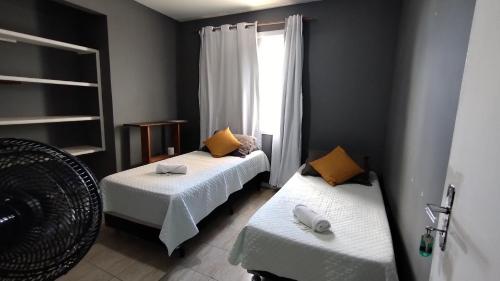 1 dormitorio con 2 camas y ventana en Pousada Jardins Campista, en Macaé