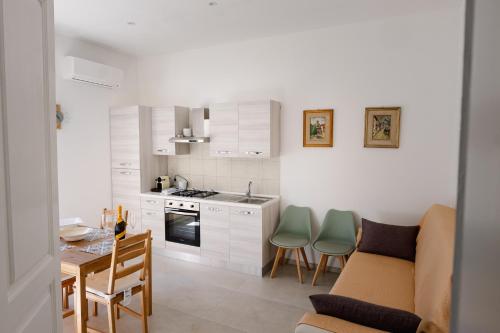 uma cozinha com armários brancos e uma mesa e cadeiras em CasaRiso em Grammichele