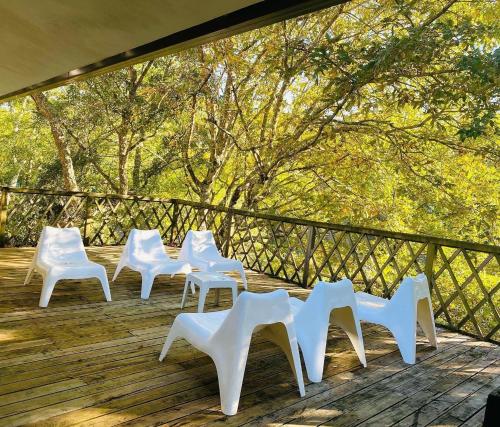 a group of white chairs sitting on a wooden deck at Quinta da Memória Village in Vimieiro