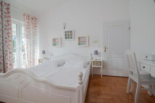 a white bedroom with a white bed and a desk at Hotel Villa Vera 2 in Fažana