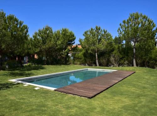 una piscina con una terraza de madera en el césped en Pool Beach & Golf Troia Reserve V3 en Grândola