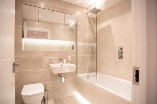 a bathroom with a toilet and a sink and a shower at Deluxe & Chic 1 & 2 Bed Apts near Heathrow, Legoland, & Windsor Slough in Slough