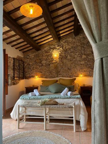 a bedroom with a bed in a stone wall at Can LLorens in Llagostera