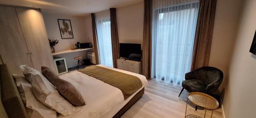 a bedroom with a bed and a chair and a television at Den Ommegang in Halle
