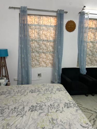 een slaapkamer met een bed, gordijnen en een stoel bij Stay with Abhishek in Gwalior