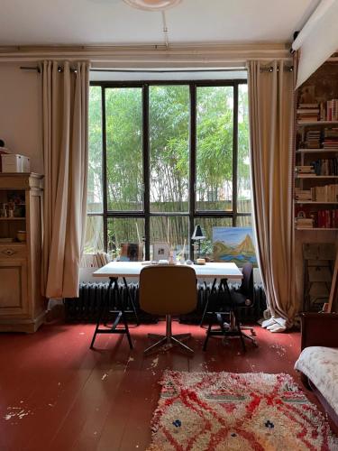 a room with a table and chairs and a large window at Warm and cosy Loft in paris with a private outdoor in Paris