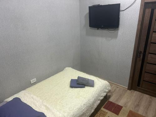 a small room with a bed with a tv on the wall at Ровный in Almaty