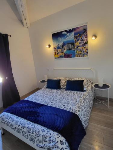 a bedroom with a bed with a blue comforter and two tables at Le Repaire du Soleil in Aigues-Mortes