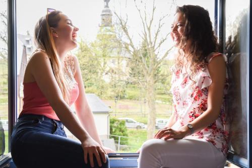 two girls sitting in a window looking out at Hotel Erbgericht Buntes Haus in Seiffen